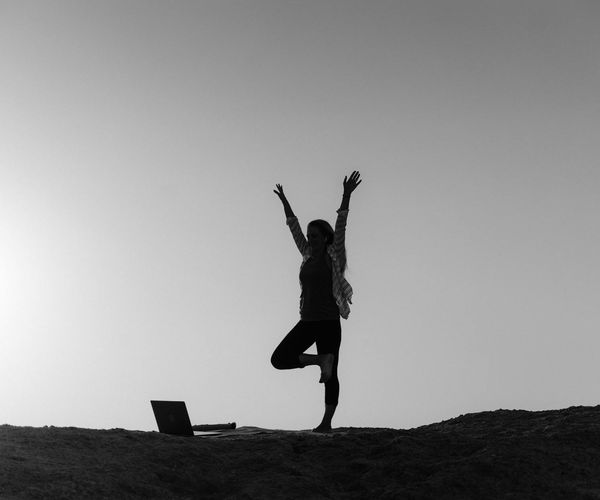 Silhouette of a person stretching during sunrise, symbolizing well-being.